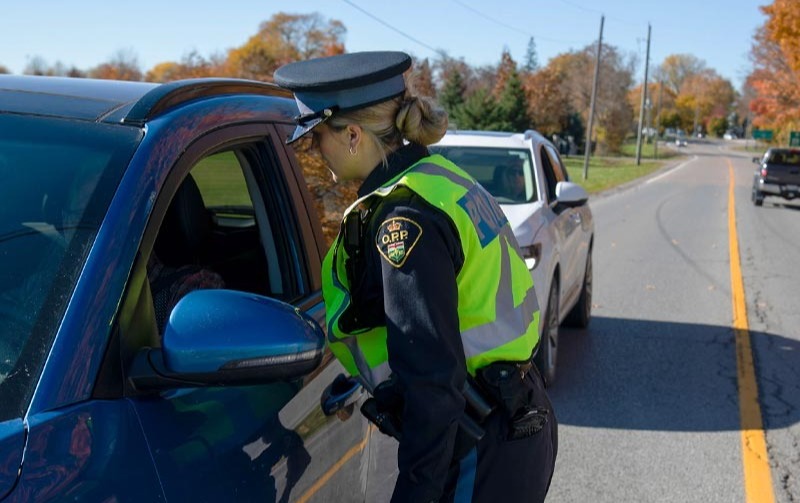 Photo of a police officer standing by a car window.